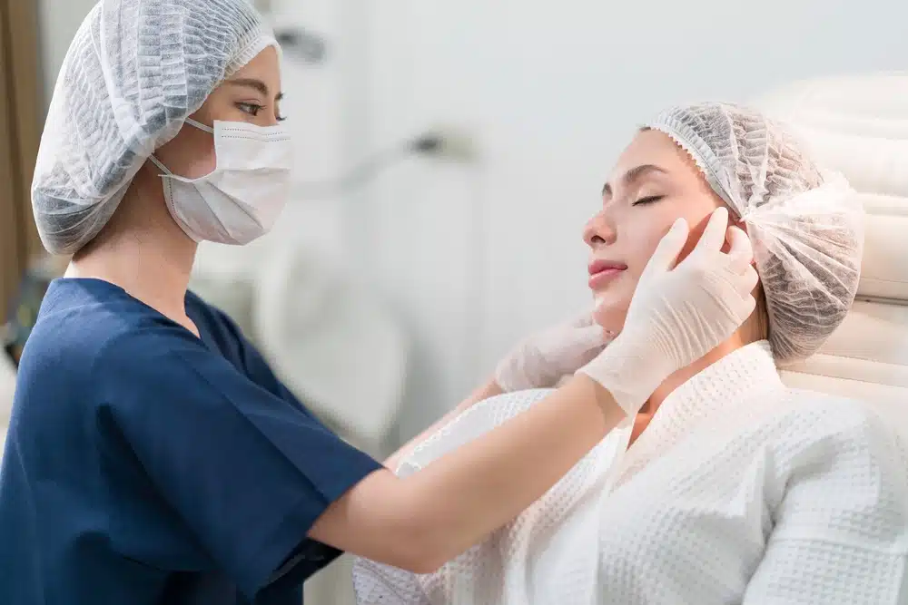 A beautician doing beauty treatment for young woman laying down